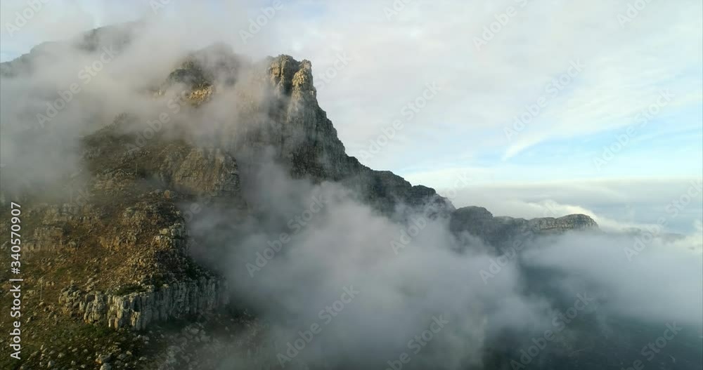 Aerial shot of a majestic mountain among clouds under blue sky, drone flying forward - Cape Town, South Africa