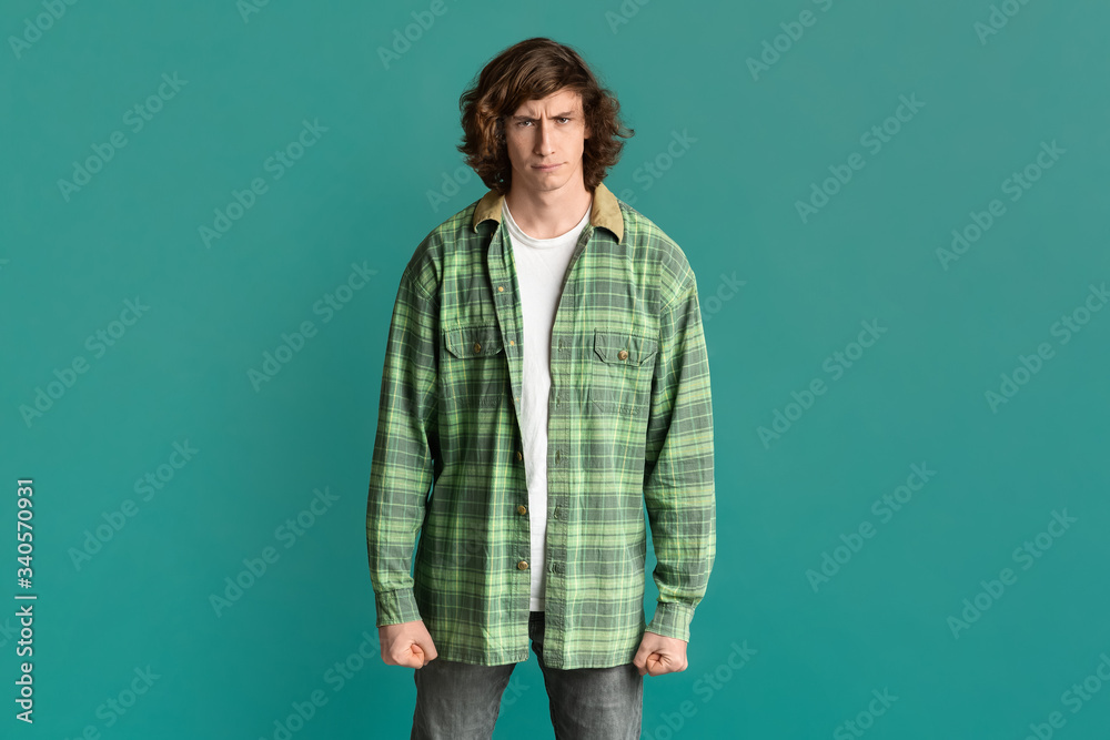 Young guy clenching his fists in anger and frowning on turquoise background Young guy clenching his fists in anger and frowning on turquoise background