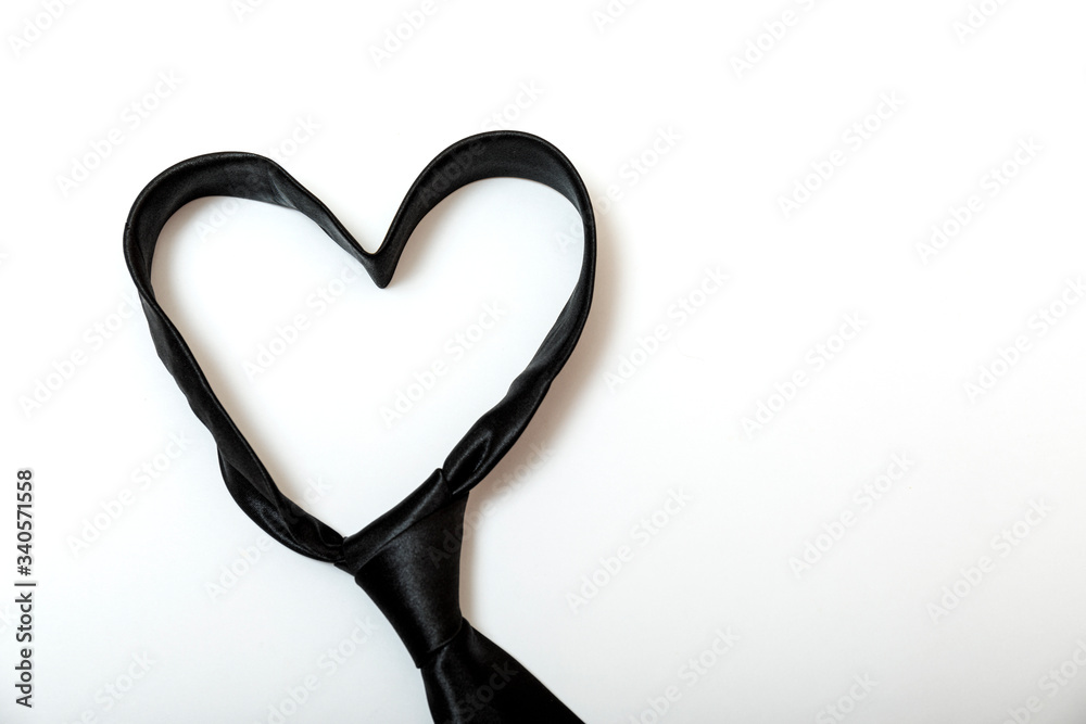 Black tie forms a heart shaped for father's day background. Minimal design on white with copy space for text.