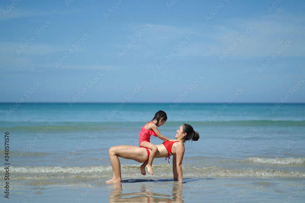Asian chinese woman spending time playing with daughter at the beach