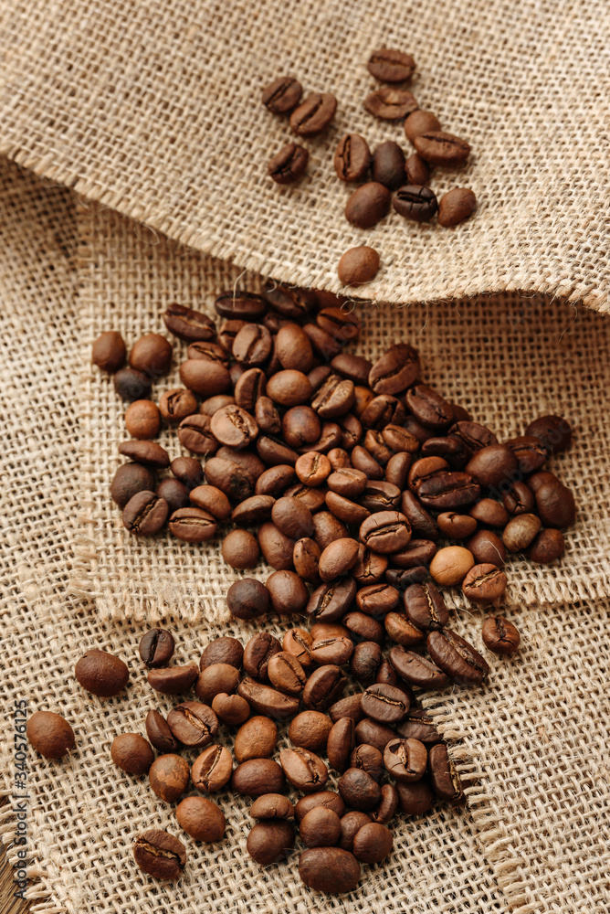 Composition with coffee beans lying on pieces of burlap with selective focus.