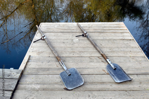 Obraz na płótnie Two oars for a boat on a wooden bridge. Clear river water.