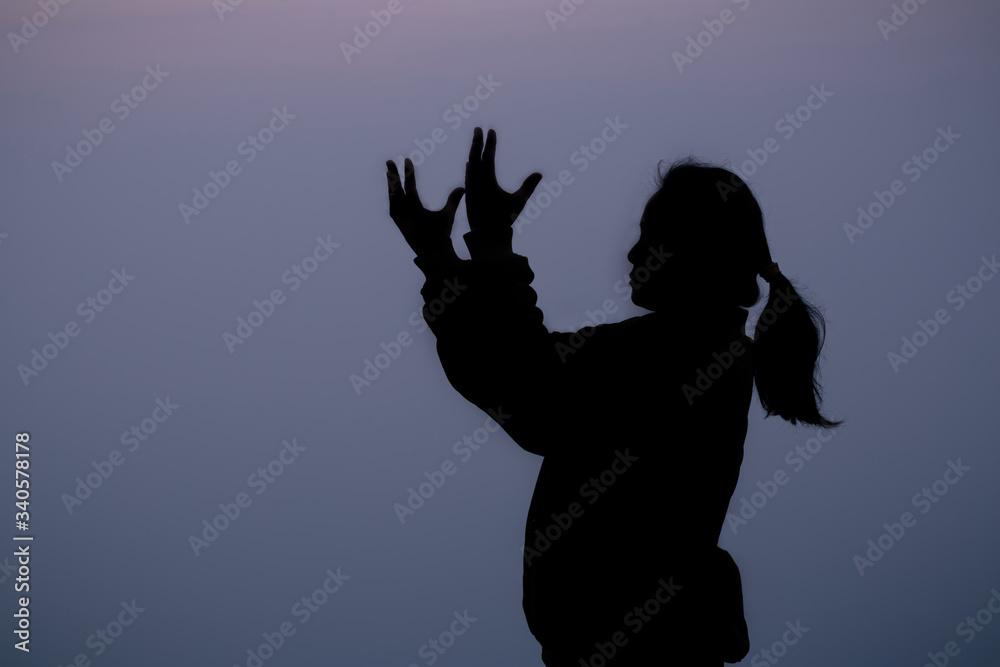 Silhouette of woman standing with arms raised on mountain