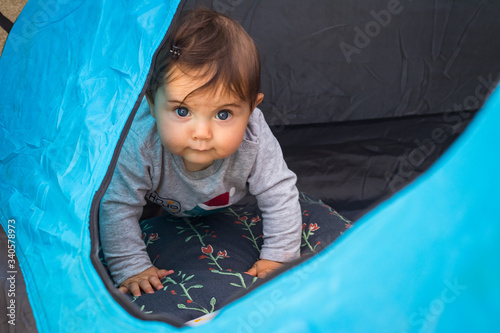 Toddler baby boy crawl and play in travelers tent.