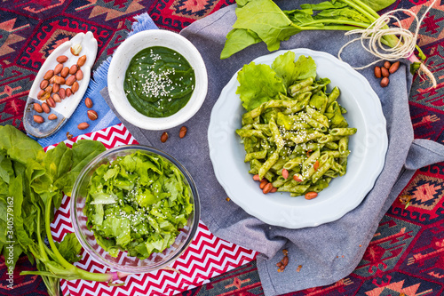 Vegan healthy food lunch meal, vegetarian dinner. Italian pesto pasta, lettuce salad. Overhead, flat lay.