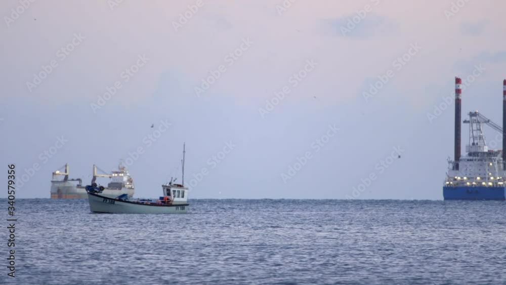 Fishing Boat. Freight Ships, and Birds Flying at Dusk or Dawn Off The Coast of Cornwall, England Fishing Boat. Freight Ships, and Birds Flying at Dusk or Dawn Off The Coast of Cornwall, England