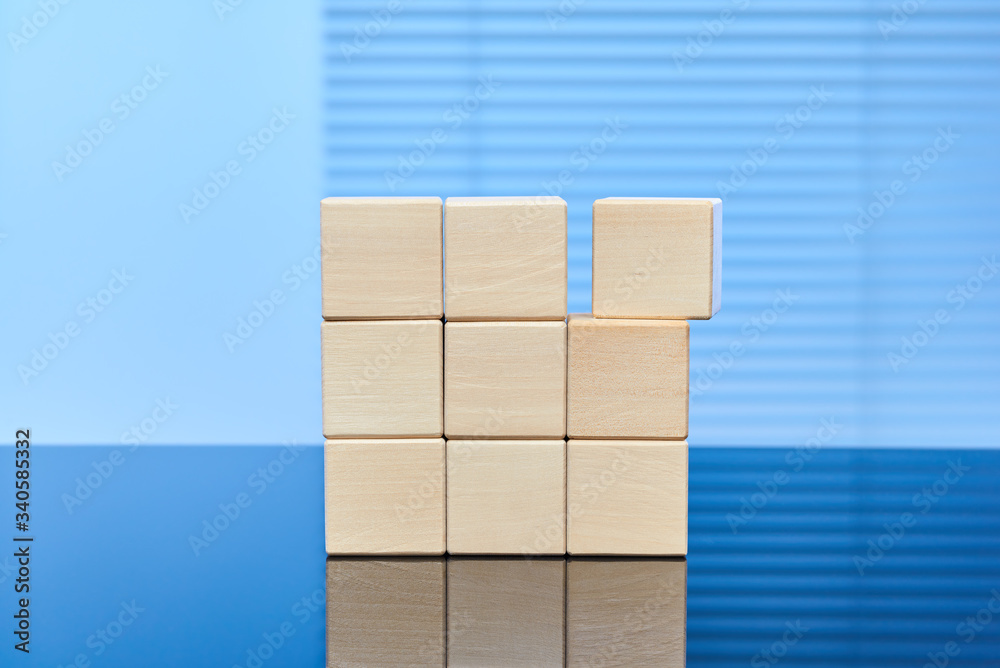 Nine wooden cubes on a blue background standing on top of each other in three rows. Free space for letters, numbers, symbols, or labels. Layout for infographics. Nine wooden cubes on a blue background standing on top of each other in three rows. Free space for letters, numbers, symbols, or labels. Layout for infographics.