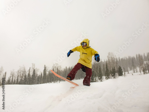 Jumping snowboarder keeps one hand on the snowboard on blue sky background