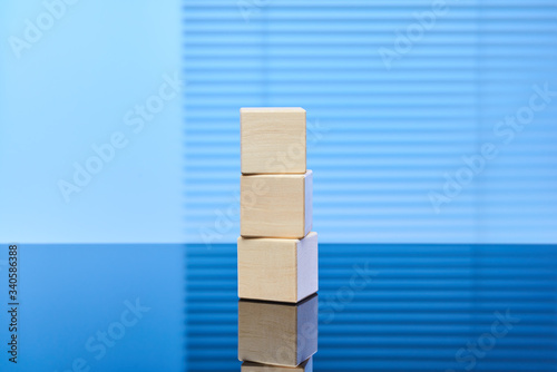 Three wooden cubes on a blue background are placed on top of each other. Free space for letters, numbers, symbols, or labels. Layout for infographics.