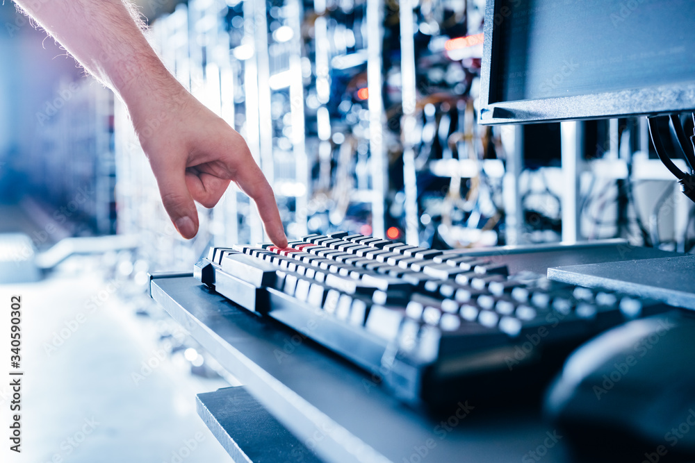IT specialist pressing red button on keyboard in big data center. IT specialist pressing red button on keyboard in big data center.