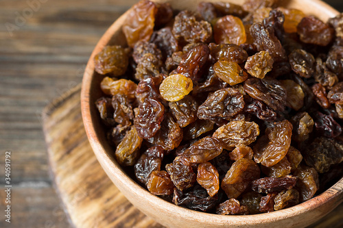 Raisins in a wooden bowl on a wooden table. Close up