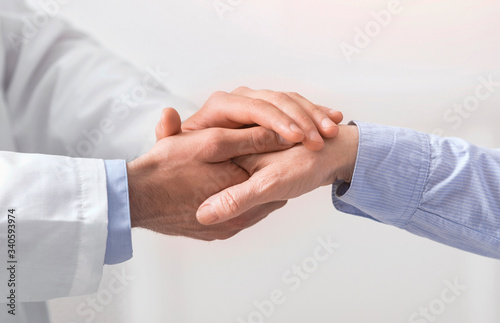 Doctor holding hand of senior woman at medical visit © Prostock-studio
