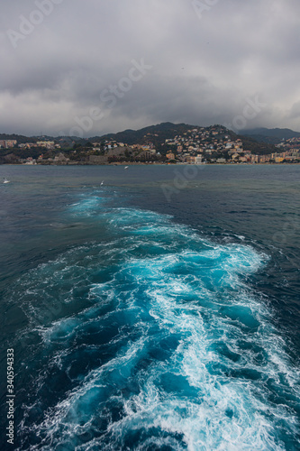 wake in blue water leaving port of Savona, Italy