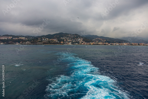 wake in blue water leaving port of Savona, Italy