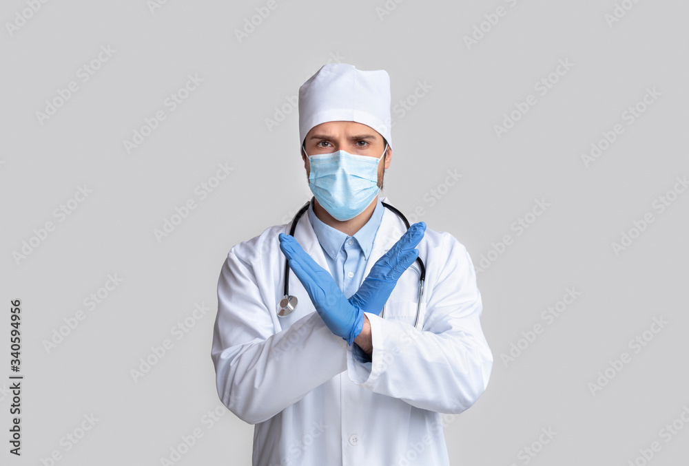 Doctor in protective wear gesturing STOP with crossed hands Doctor in protective wear gesturing STOP with crossed hands