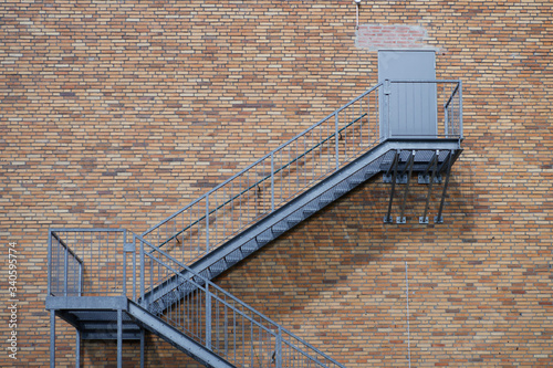 Exterior steel staircase leading to a closed door on a red brick building wall.