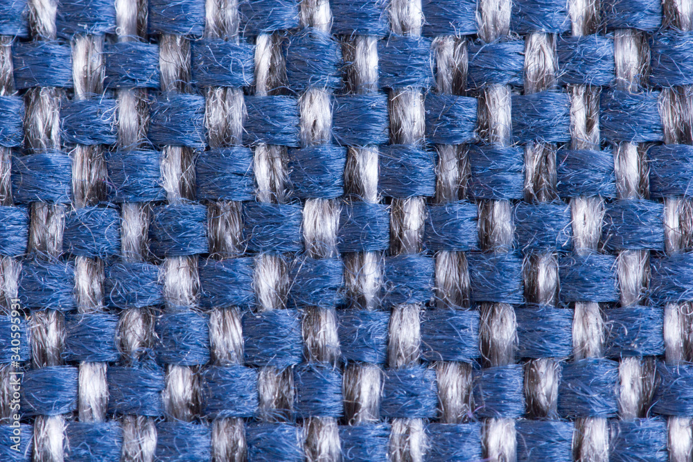Fototapeta premium Abstract background from the upholstery fabric of the matting for furniture in a large knit of black and blue threads in macro, empty template. Gunny. Large weaving of threads on the fabric.