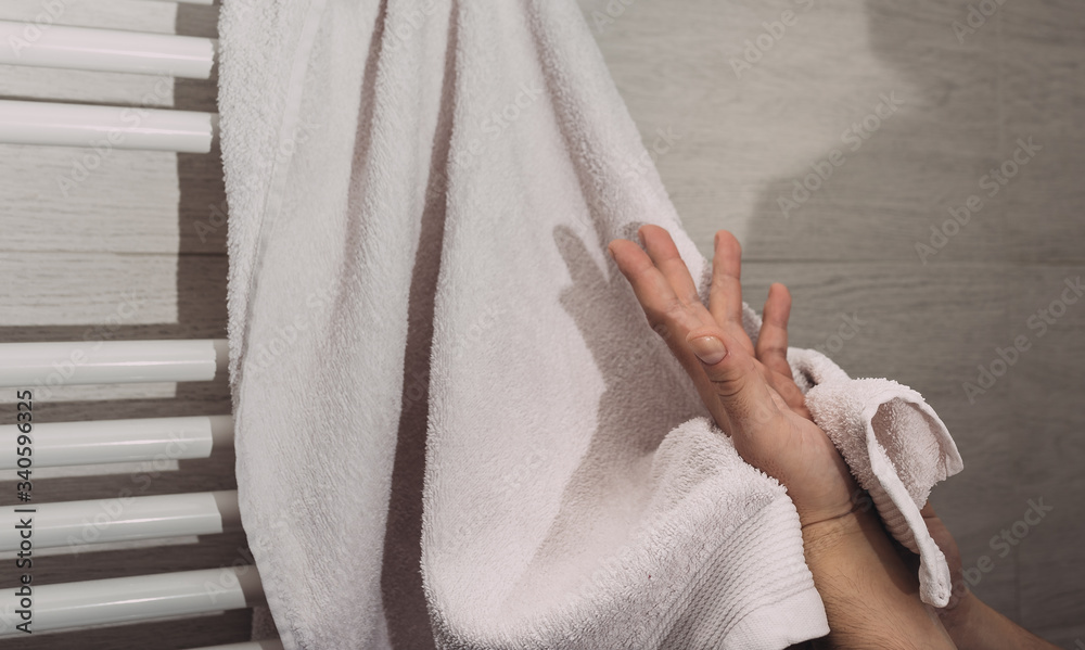 Person using towel for wiping hands dry after washing in bathroom at home. Hygiene and hand care