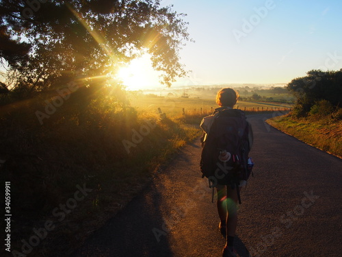 Pilgrim and bright morning sun and beautiful agricultural landscape, Camino de Santiago, Way of St. James, Journey from Olveiroa to Negreira, Fisterra-Muxia way, Spain photo