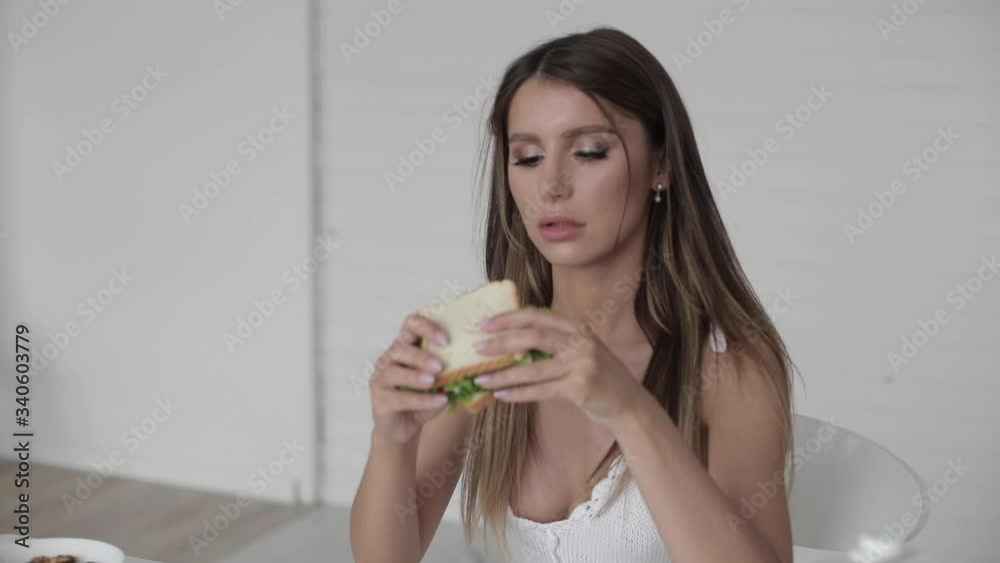 Portrait of beautiful woman with long hair eats healthy sandwich, have a lunch at home Portrait of beautiful woman with long hair eats healthy sandwich, have a lunch at home