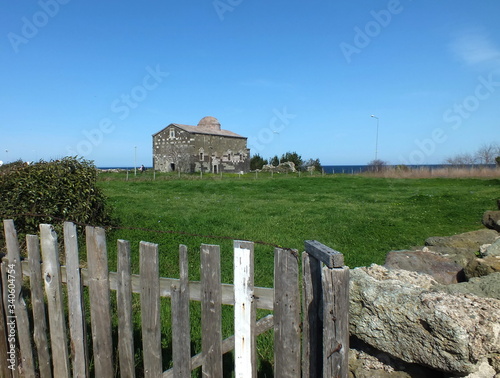 north turkish Church. Simple orthodox stone church on green meadow behind rural fence. Black Sea and blue Sky making a low horizon.