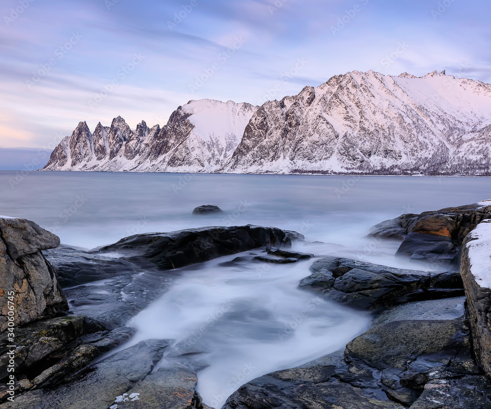 The rocky beach and frozen waves in pool on Ersfjord. Senja island in the Troms region of northern Norway. Long exposure shot