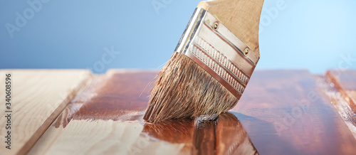 Bilde på lerret Painting wooden floor with protective varnish on a blue background