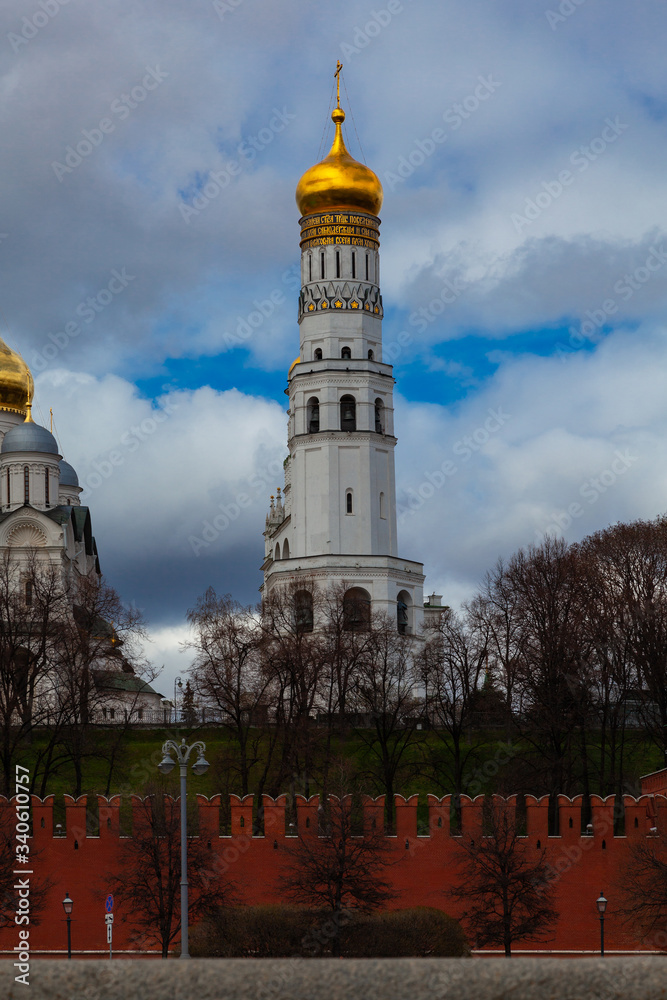 The bell tower of Ivan the Great on the territory of the Moscow Kremlin. In the foreground is a fortress wall