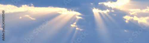 Canvas Print The sun's rays break through the blue clouds