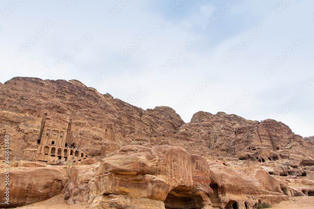 Facades of old rock houses against a blue sky with white clouds in ancient Petra in Jordan