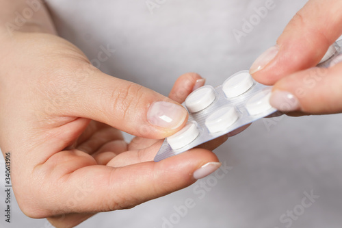 Female hand with a pill in foil packaging