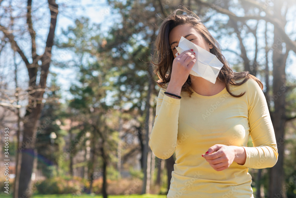 Fototapeta premium Young woman with with allergy symptom blowing nose