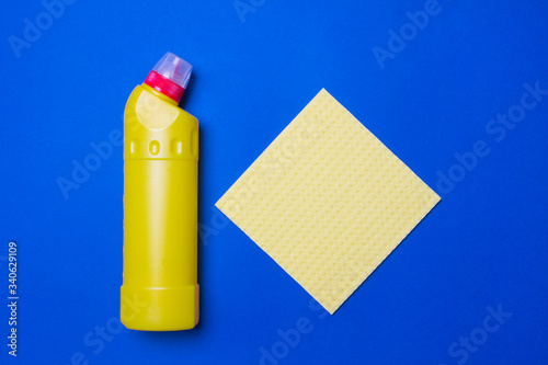 yellow bottle with cleaning agent and napkin on whiteblue background  top view photo