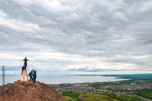 Unrecognizable tourists observing the panorama of Edinburgh from Arthur s Seat