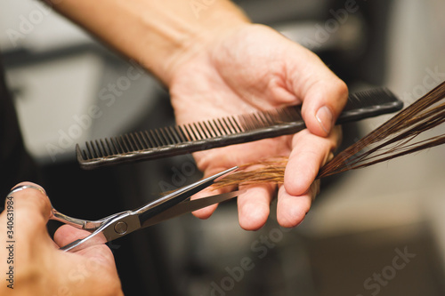 Hairdresser male hands during cutting female hair