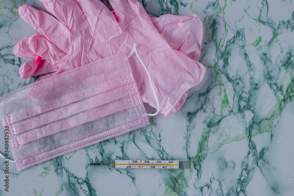 Pink medical mask, pink medical gloves and a thermometer. Coronavirus concept. Pink medical mask, pink medical gloves and a thermometer. Coronavirus concept.