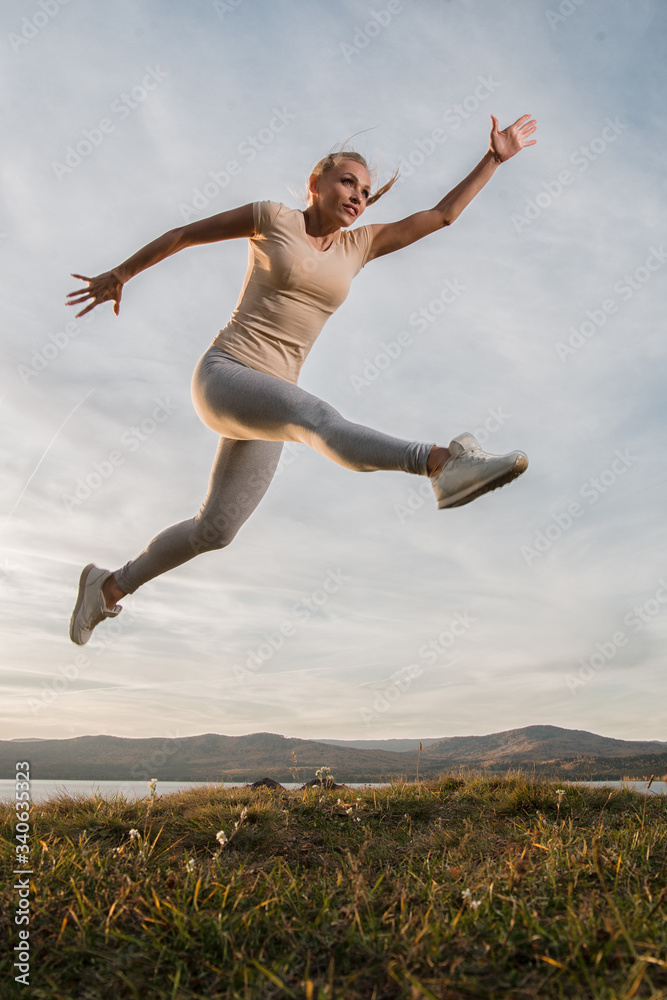 A beautiful woman, a fitness instructor, in light clothing, trains on the beach, against the sky. Shows exercises from yoga, Pilates, Deep Work, Step aerobics A beautiful woman, a fitness instructor, in light clothing, trains on the beach, against the sky. Shows exercises from yoga, Pilates, Deep Work, Step aerobics