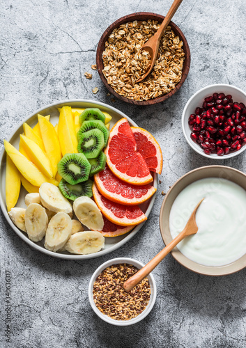Breakfast set table - fresh tropical fruits, greek yogurt, granola on a gray background, top view. Delicious healthy diet food concept. Flat lay