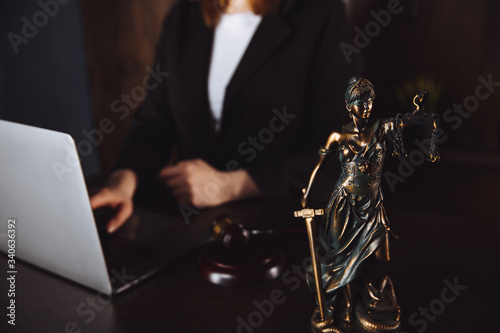 Lawyer office. Statue of Justice with scales and lawyer working on a laptop. Legal law, advice and justice concept.