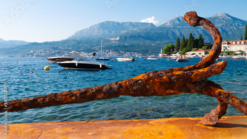 Big rusty ship anchor in front of a small marina of the village of Rose - Rose Village  Lustica peninsula  Kotor Bay  Montenegro  Europe.
