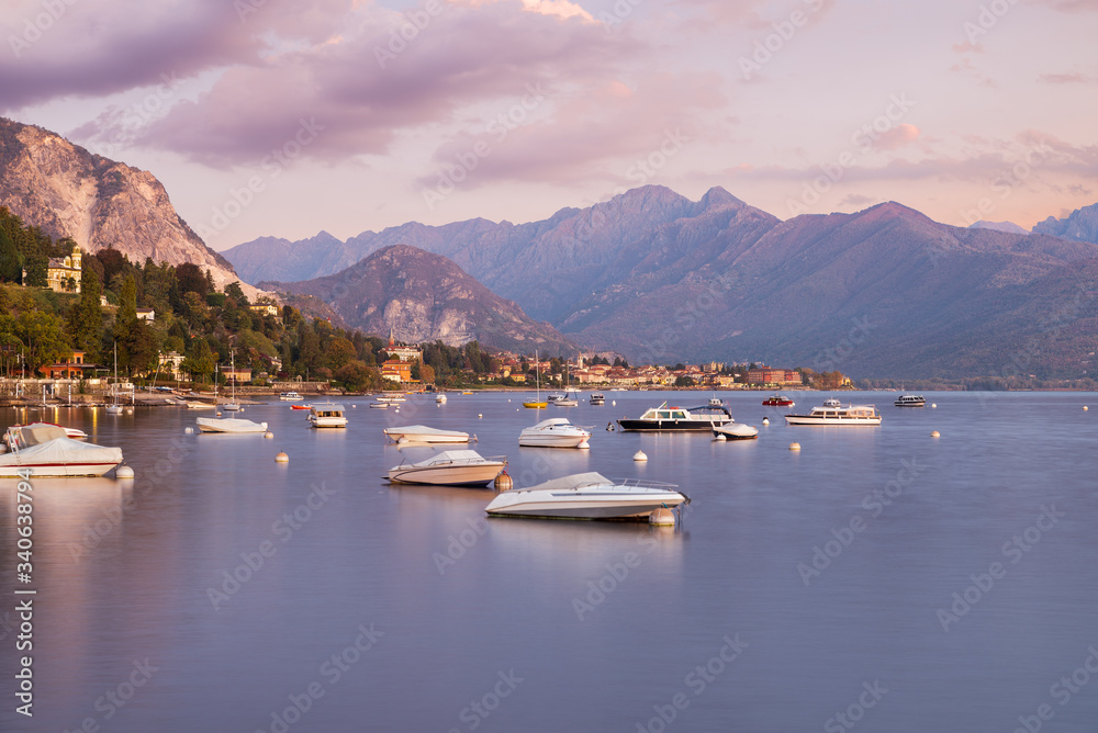 Lake Maggiore at sunrise, Italy. Panorama from the lakefront of the town of Stresa towards Baveno with boats and silk water effect