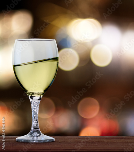 A glass of white wine in front of blured city lights. A tilt has been added for more dynamic.