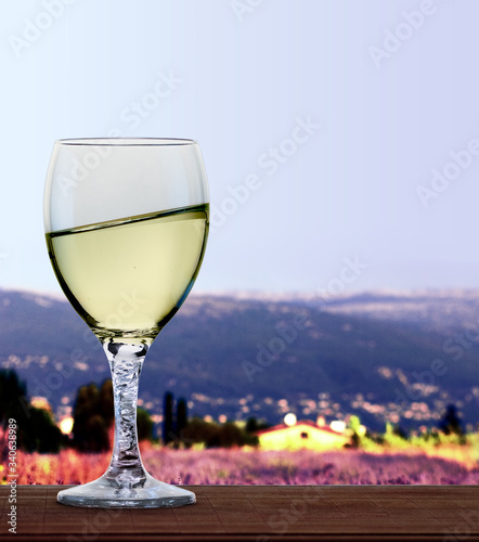 A glass of white wine in front of French alps and lavender fields. A tilt has been added for more dynamic. 