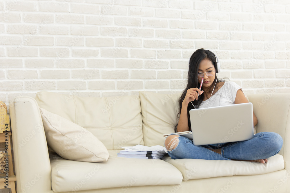 A young Asian woman working online from home. A young Asian woman working online from home.