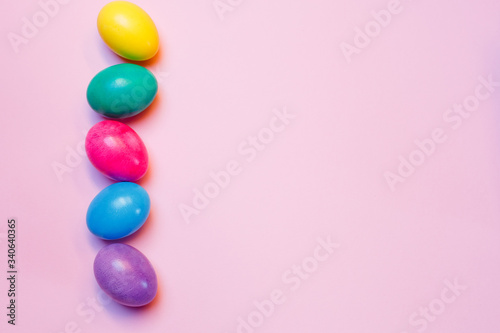 Decorated with colorful Easter eggs and space for text on a pink background, top view