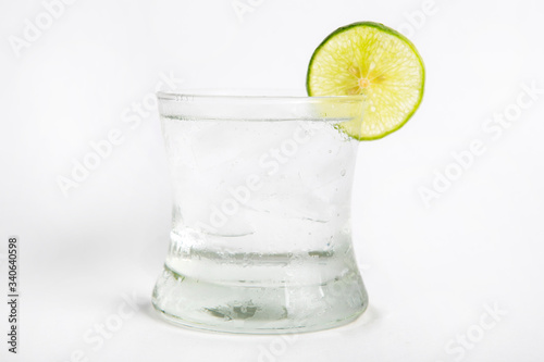 gin tonic in a glass decorated by sliced lime white background