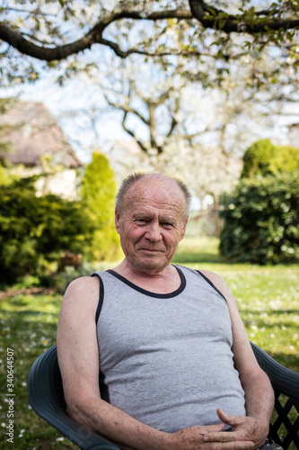 Portrait of senior man sitting in chair at his garden