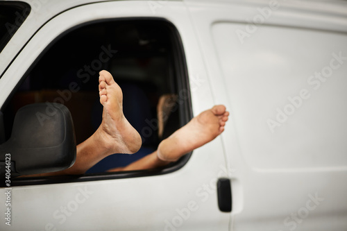 A worker rests his feet while sleeping in his van