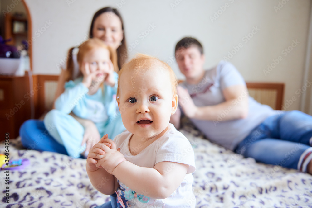Red-haired girl sitting in front of the family on the bed Red-haired girl sitting in front of the family on the bed