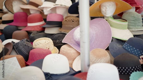 A pile of different types and styles of summer panama hats and caps displayed on local market counter. Trading on flea market, textile production, handmade accessories photo
